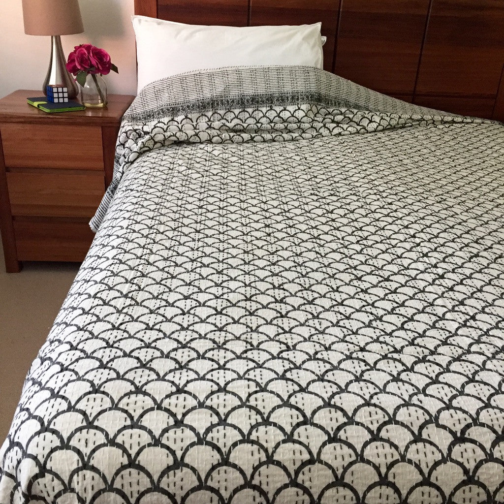Monochrome quilt is hand block printed with prominent border design and has been embellished with traditional Kantha running stitch. Block printing and Kantha are amongst the oldest forms of art from India. 